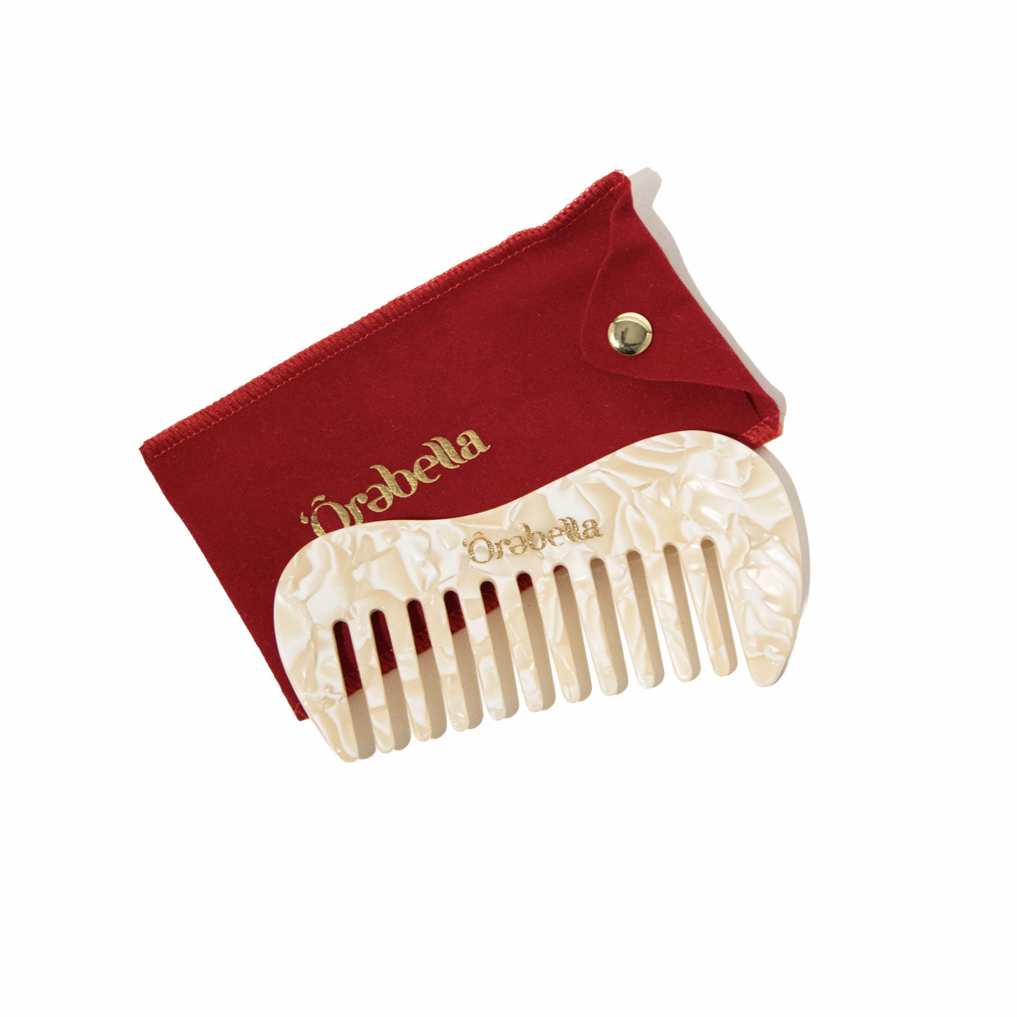 Red velvet pouch and cream shell comb displayed together at an angle