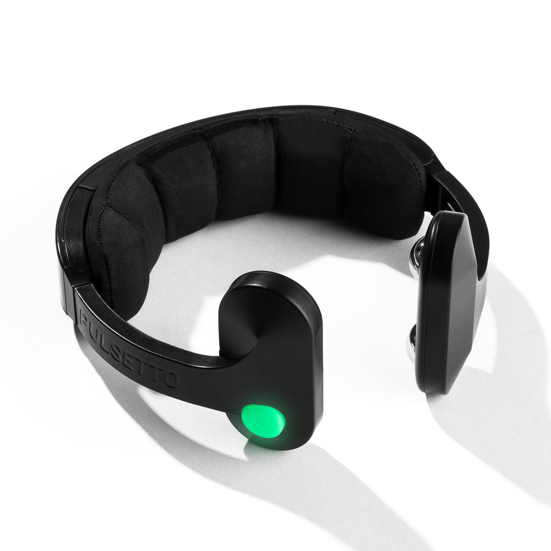 Black wearable neck device with fabric band and green illuminated button on the control unit