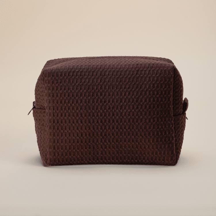 Dark brown textured waffle pouch with side handles against neutral background