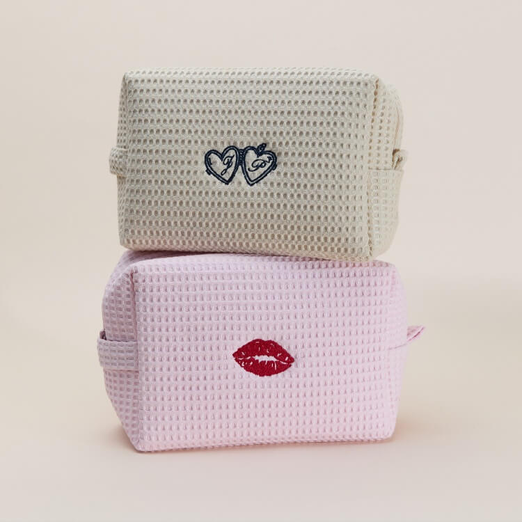 Stacked cream and pink waffle-textured pouches with embroidered heart and lips designs