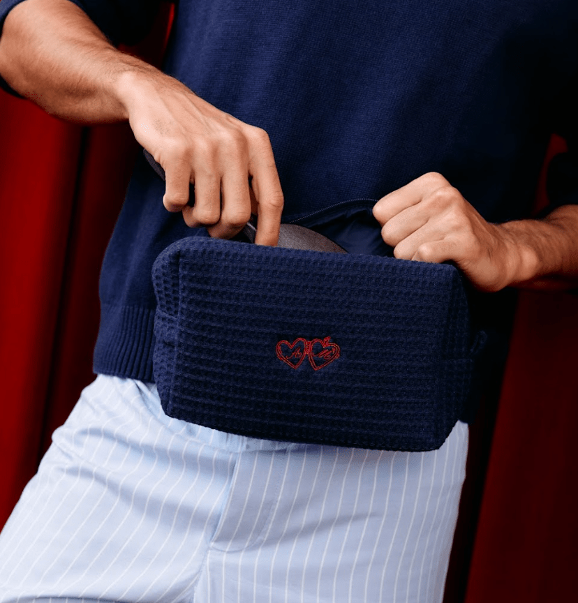 Person wearing navy blue knit clutch with red embroidered double heart design