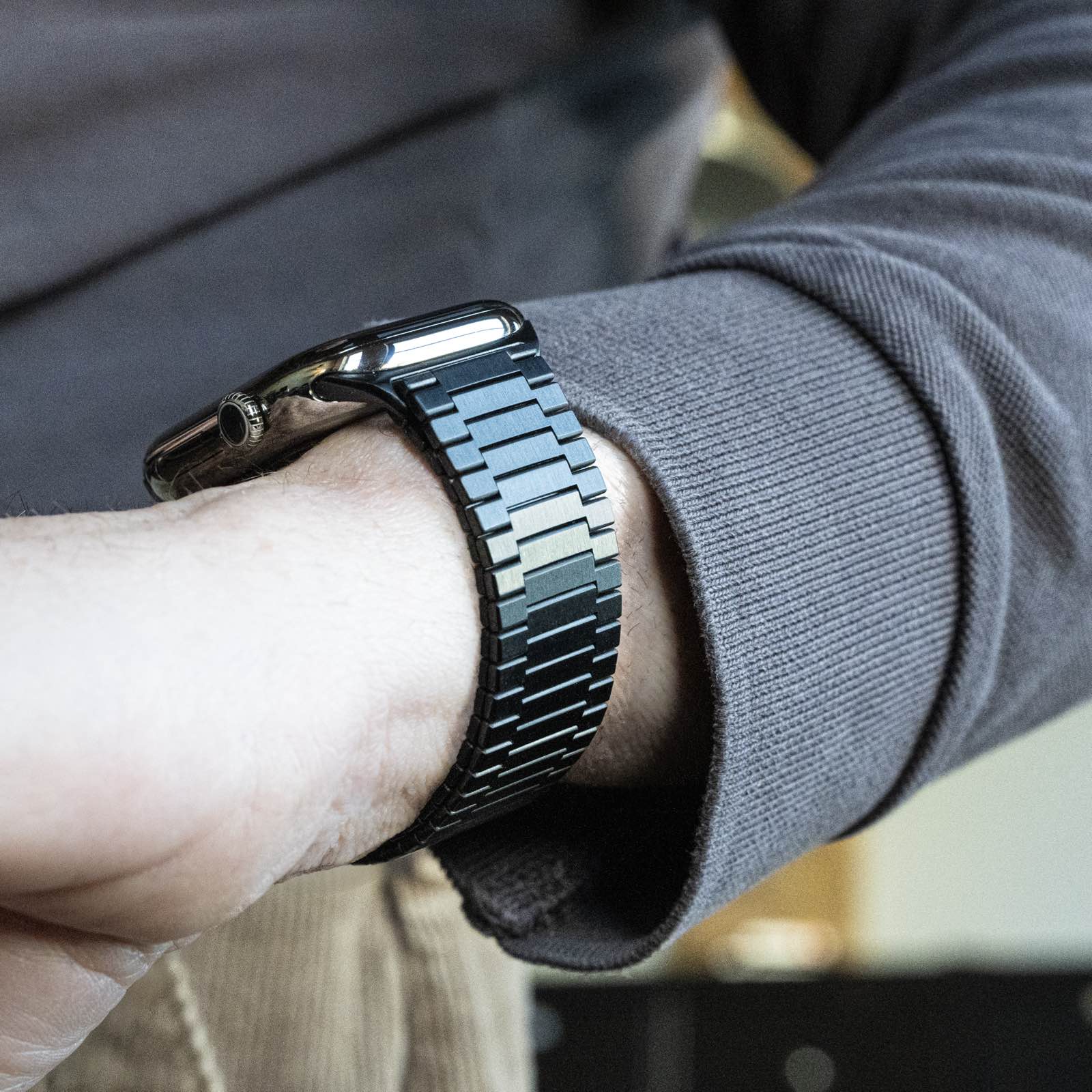 Black metal link watch band on person's wrist wearing gray sweater
