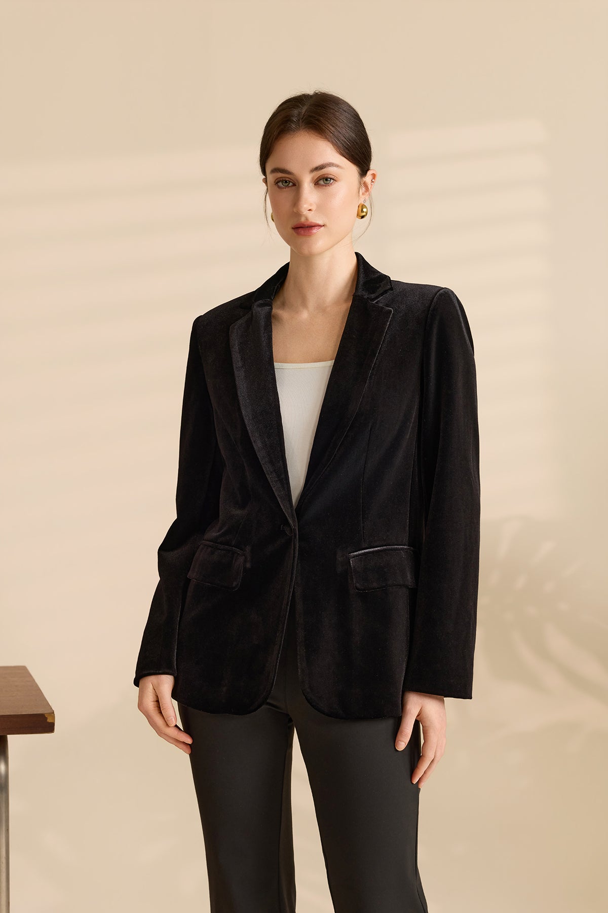Woman wearing black velvet blazer over white top with gold hoop earrings