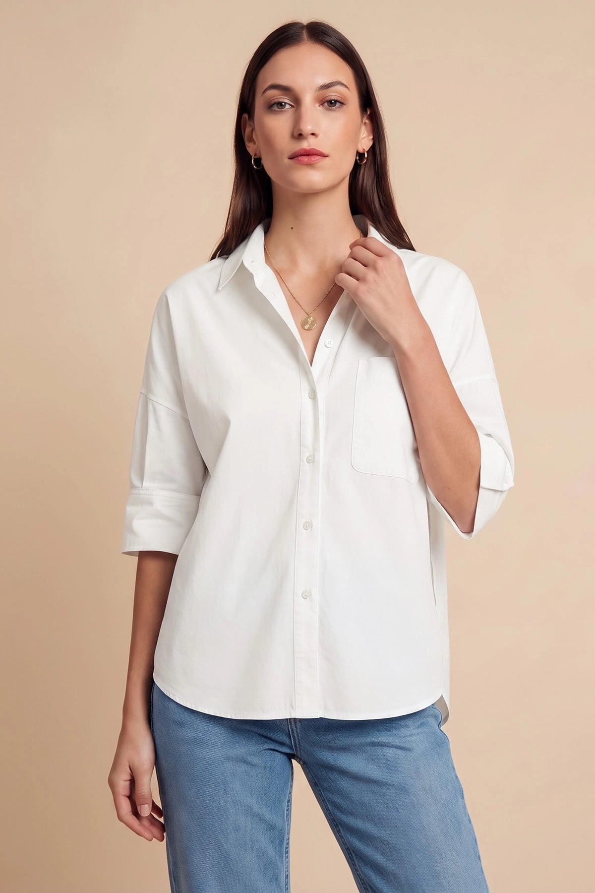 Woman in white button-up shirt with three-quarter sleeves and pendant necklace