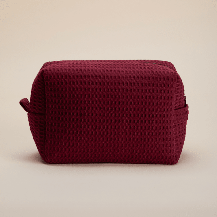 Deep burgundy textured pouch with side handles and zipper detail