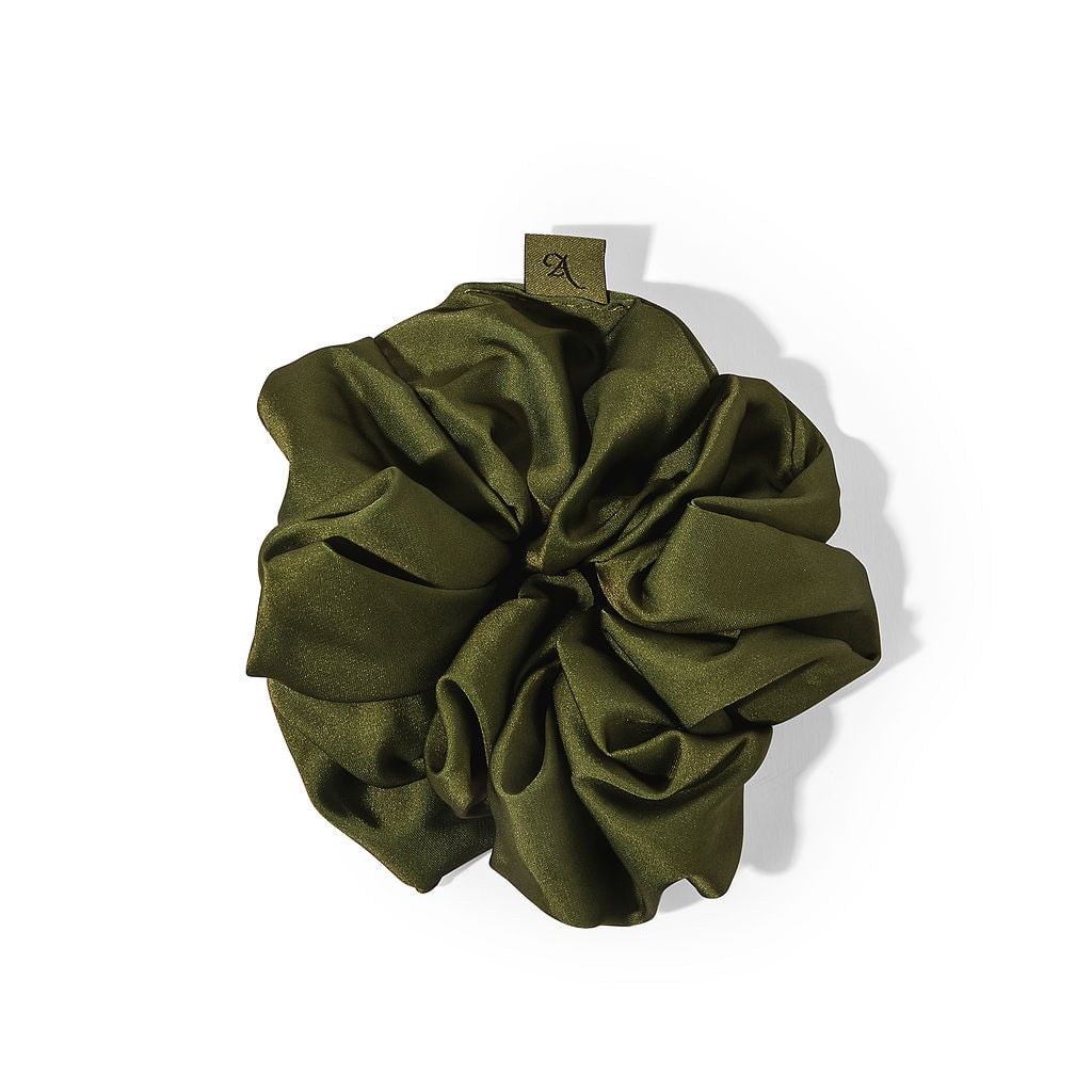 Olive green silk scrunchie with gathered fabric and small tag detail against white background